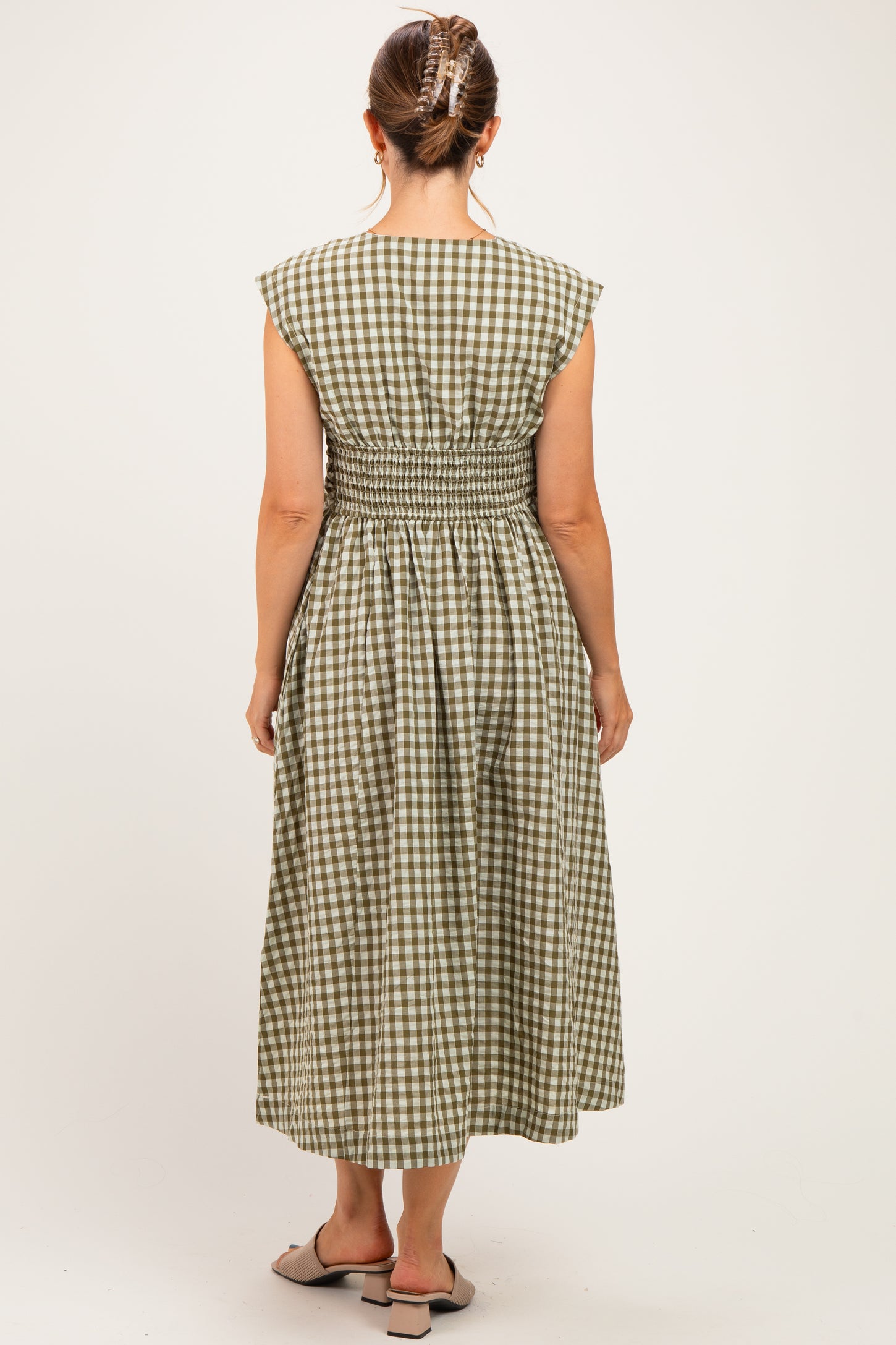 woman wearing a green and white checkered maternity dress with a smocked waist, showing the back design
