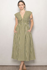woman wearing a green and white gingham midi dress with cap sleeves and side pockets