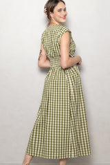 woman wearing a green and white checkered midi dress with cap sleeves and a cinched waist, smiling at the camera
