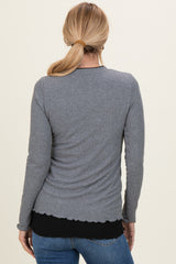 woman wearing a gray long sleeve top with a scalloped hem and styled with dark blue jeans, view from the back