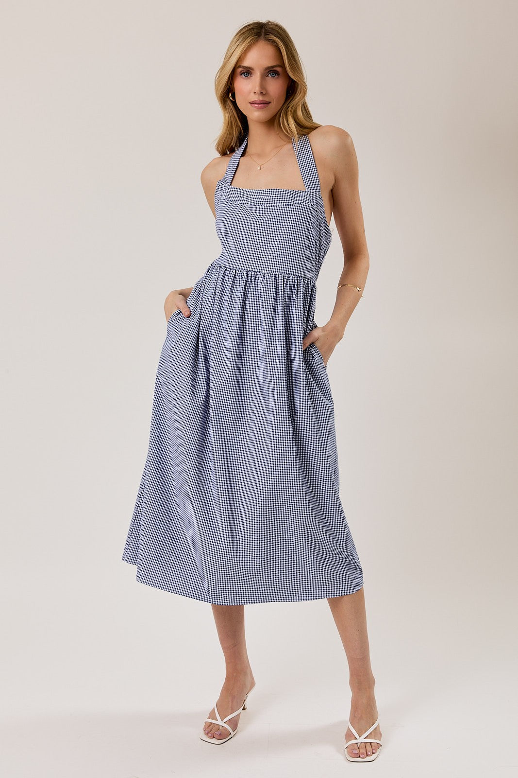 woman wearing a blue and white gingham halter neck midi dress with pockets