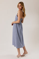 woman wearing a blue and white gingham halter neck mid-length dress, standing with her back to the camera