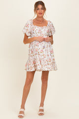 woman wearing a floral maternity dress with puff sleeves and a square neckline, smiling at the camera