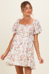 woman wearing a floral print white maternity dress with puff sleeves and a square neckline