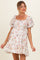 woman wearing a floral print white maternity dress with puff sleeves and a square neckline