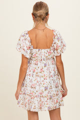woman wearing a floral print maternity dress with puff sleeves and a tiered hem, showing a bare back
