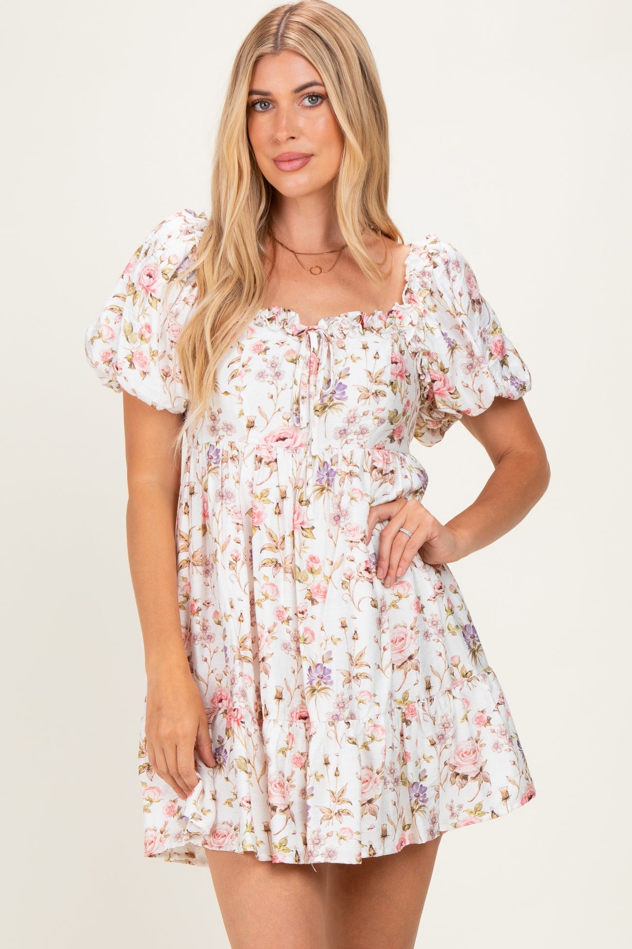 woman wearing a white floral puff sleeve mini dress with a square neckline and gathered waist