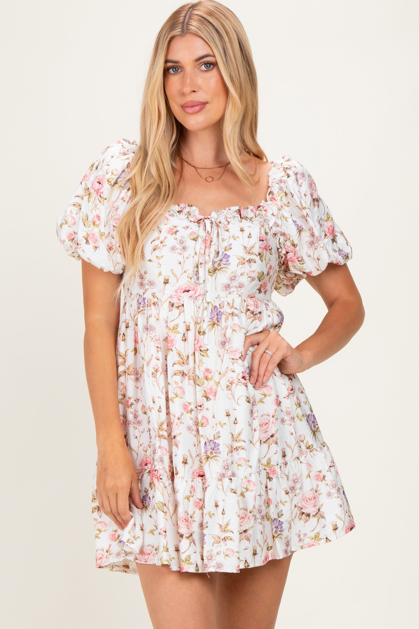 woman wearing a white floral puff sleeve mini dress with a square neckline and gathered waist
