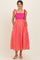 woman wearing a pink and red striped maternity dress with a smocked bodice and tie straps, showing a baby bump