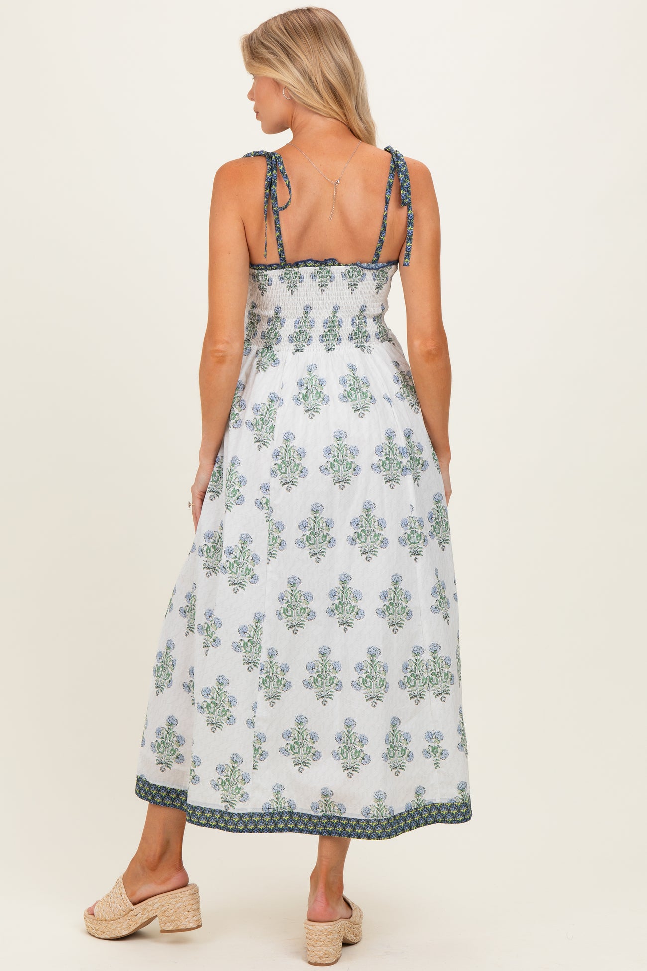woman wearing a maternity maxi dress with blue and green floral patterns and adjustable straps