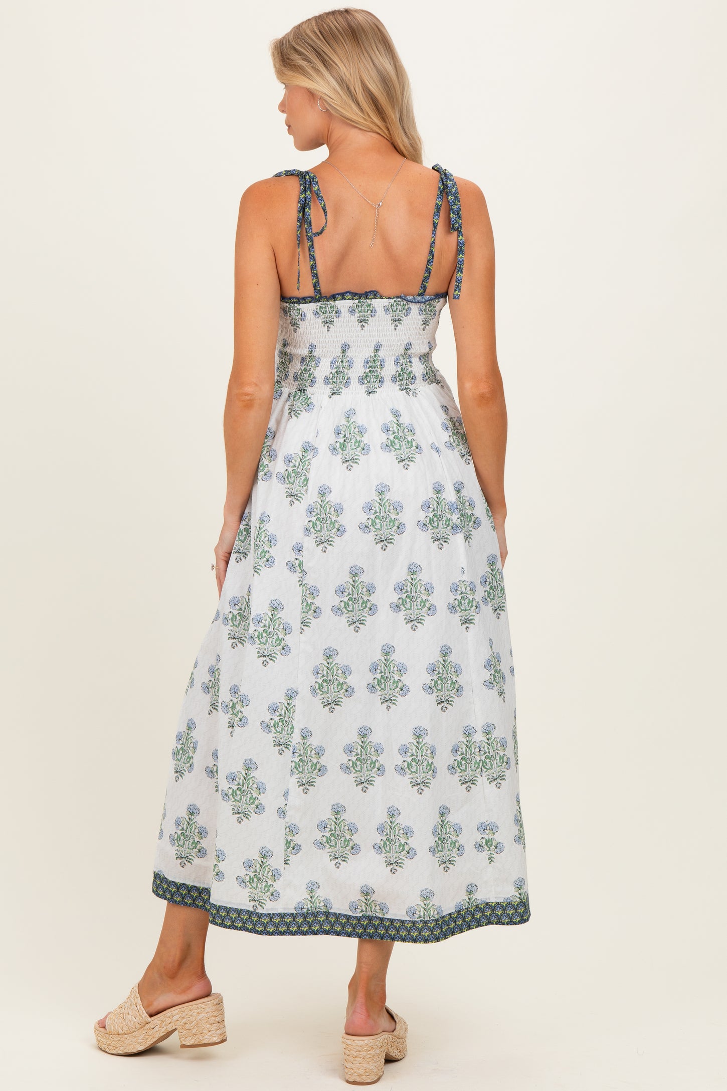 woman wearing a maternity maxi dress with blue and green floral patterns and adjustable straps