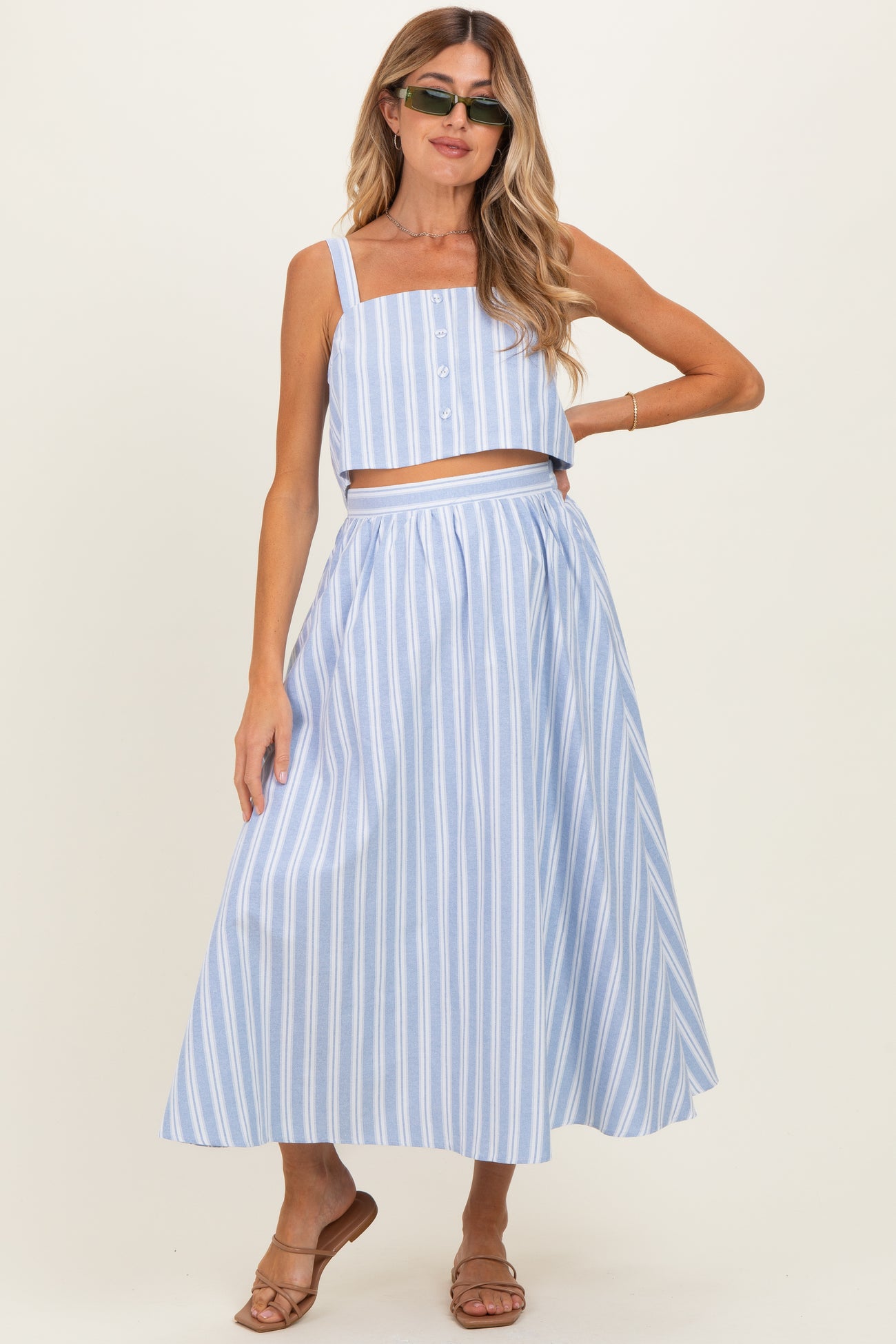 woman wearing a light blue striped maternity two-piece set with a crop top and long skirt, showcasing a baby bump