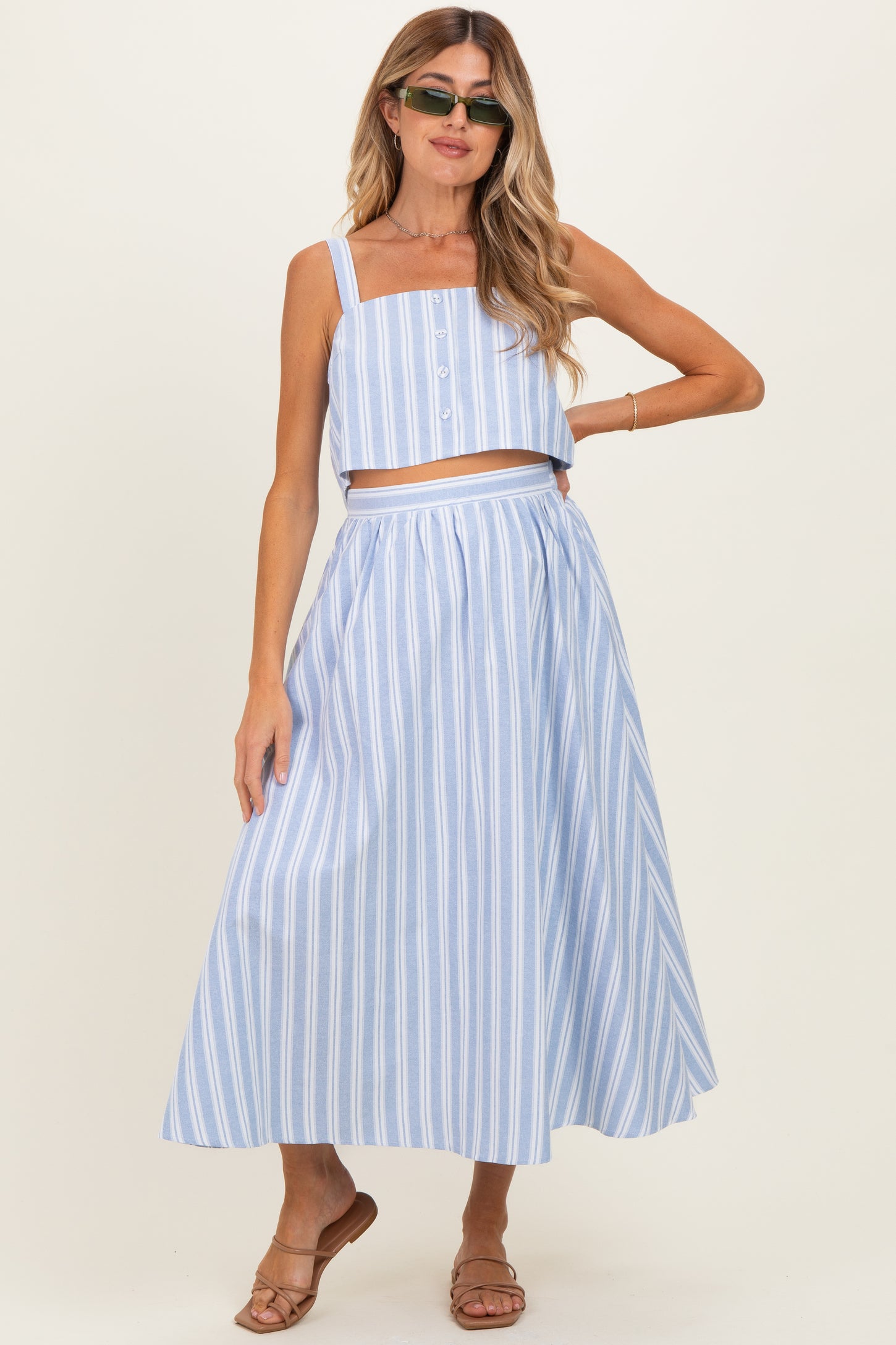 woman wearing a light blue striped maternity two-piece set with a crop top and long skirt, showcasing a baby bump
