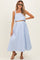 woman wearing a light blue striped maternity two-piece set with a crop top and long skirt, showcasing a baby bump