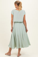 woman wearing a mint green maternity dress with a flowy skirt and short sleeves, viewed from the back