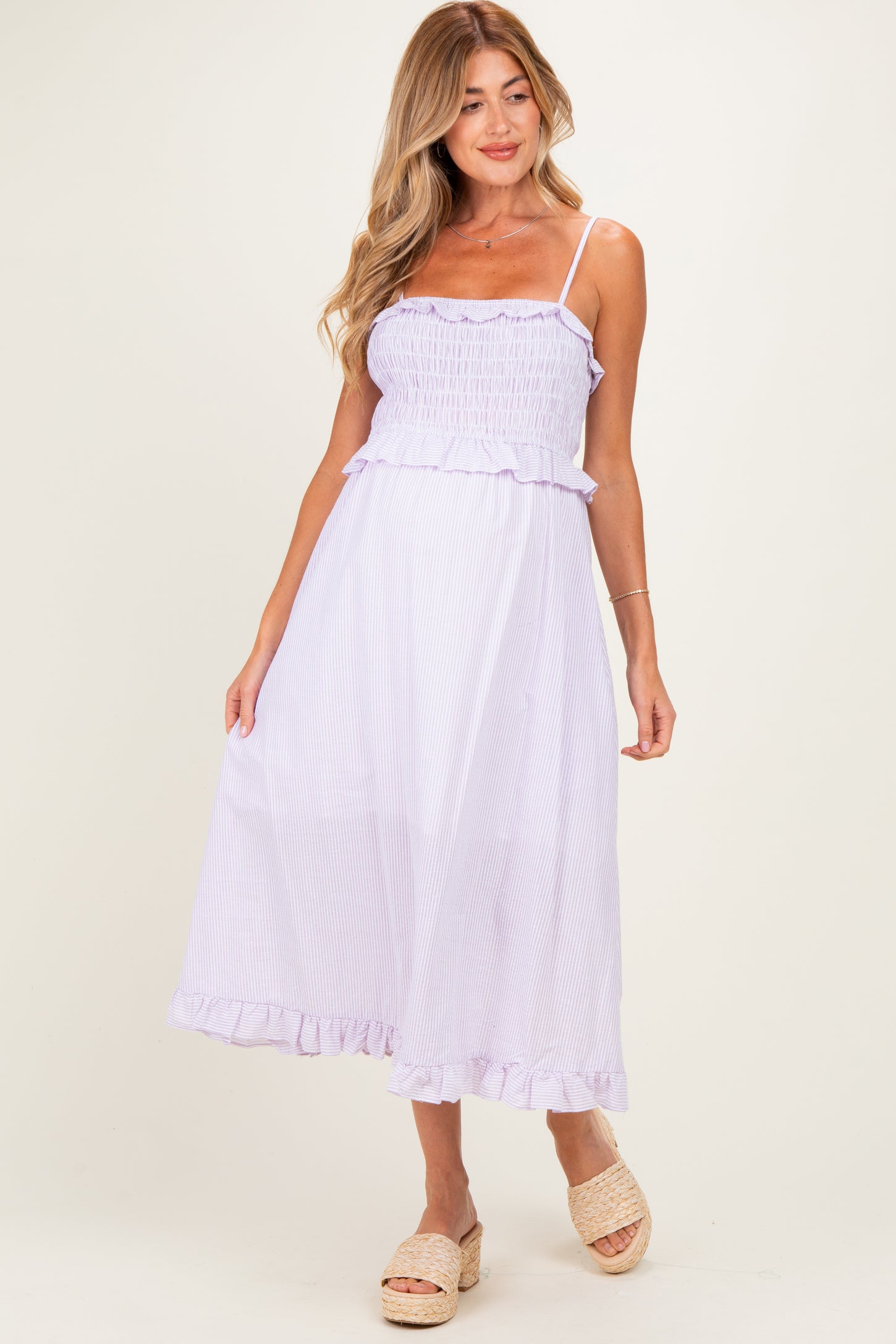 woman wearing a lavender striped maternity dress with ruffle details and adjustable straps