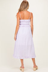 woman wearing a lavender striped maternity dress with a smocked bodice and ruffled hem, showcasing a baby bump
