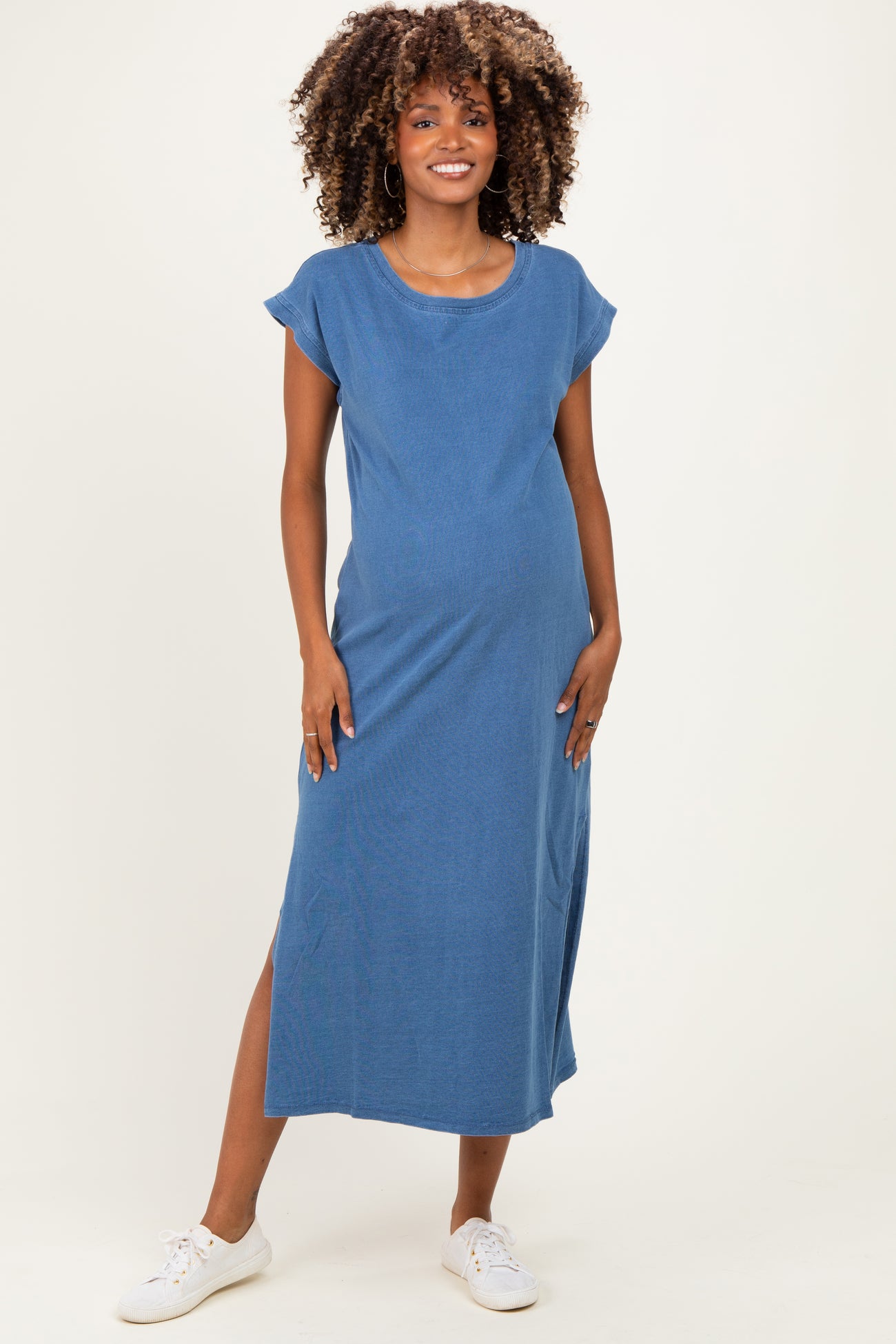 woman wearing a blue maternity maxi dress with short sleeves and side slits, displaying a visible baby bump
