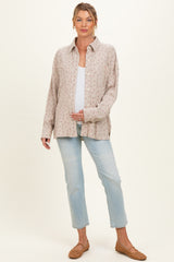 woman wearing a floral print maternity shirt with buttons and holding her baby bump, paired with light blue jeans