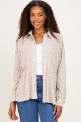 woman wearing a light beige button-up shirt with floral print and a pocket, paired with high-waisted blue jeans