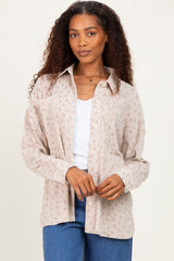 woman wearing a cream floral button-up shirt over a white top and blue jeans