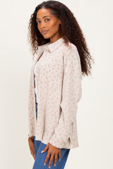 woman wearing a light beige floral button-up shirt with long sleeves and relaxed fit paired with blue jeans