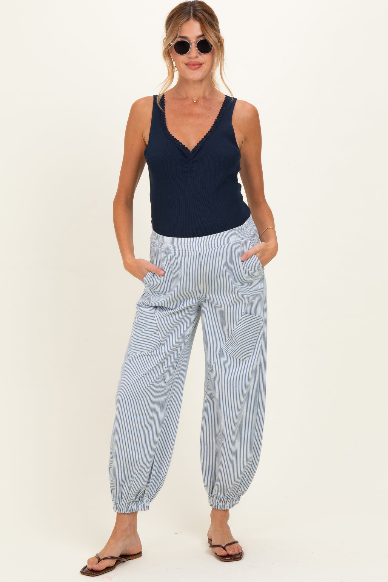 woman wearing a navy blue maternity tank top and blue and white striped maternity pants with pockets