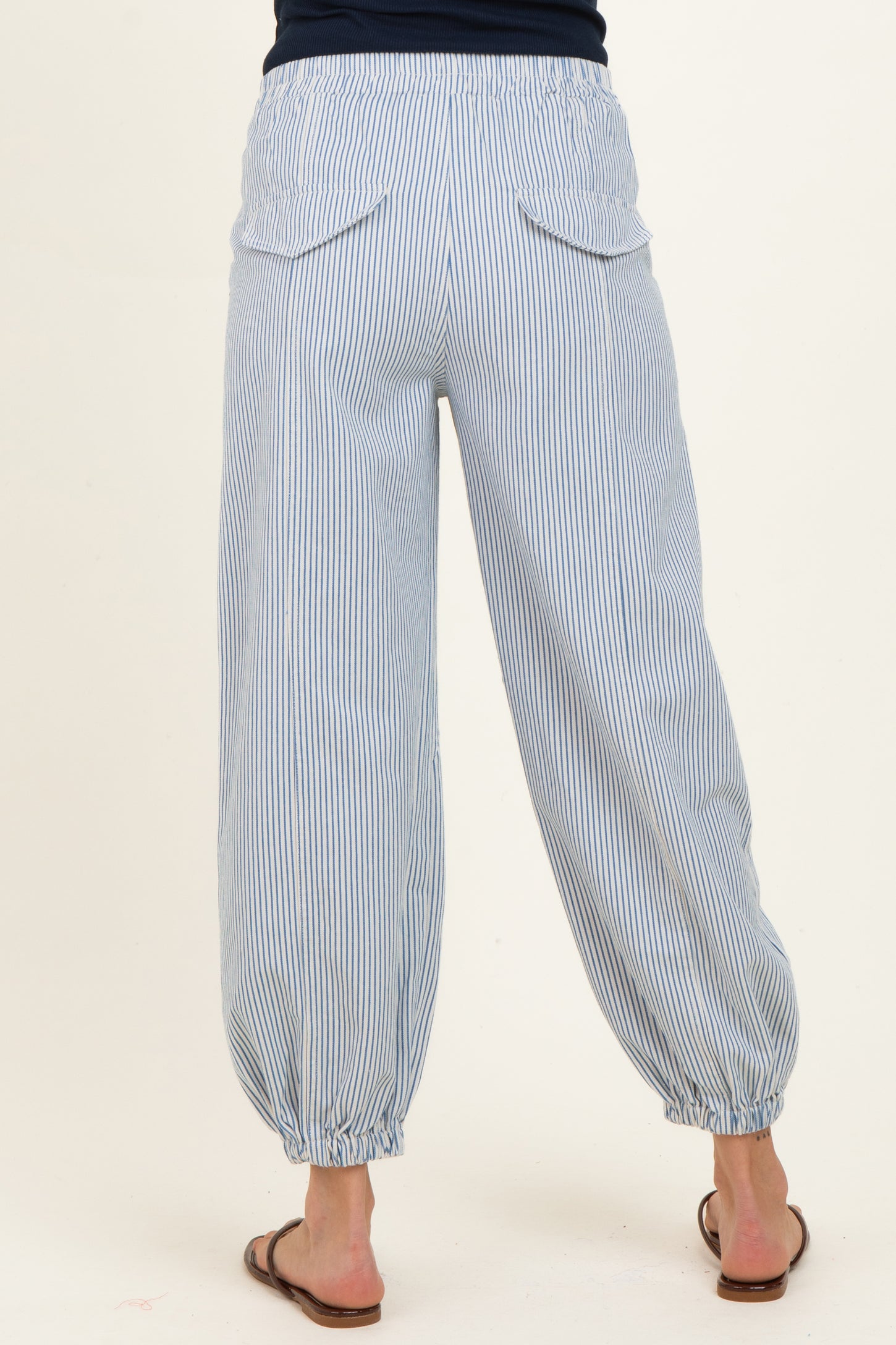 woman wearing light blue striped maternity pants with an elastic waistband and gathered cuffs, showing the back view