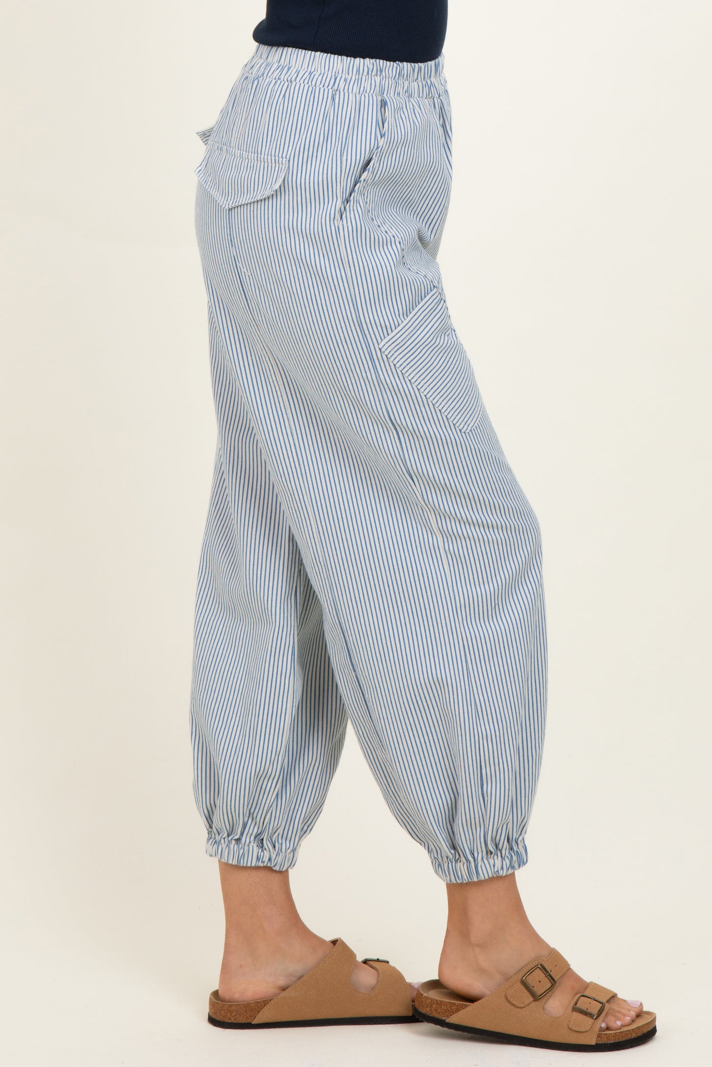 woman wearing blue and white striped cropped pants with elastic cuffs and side pockets, paired with tan sandals