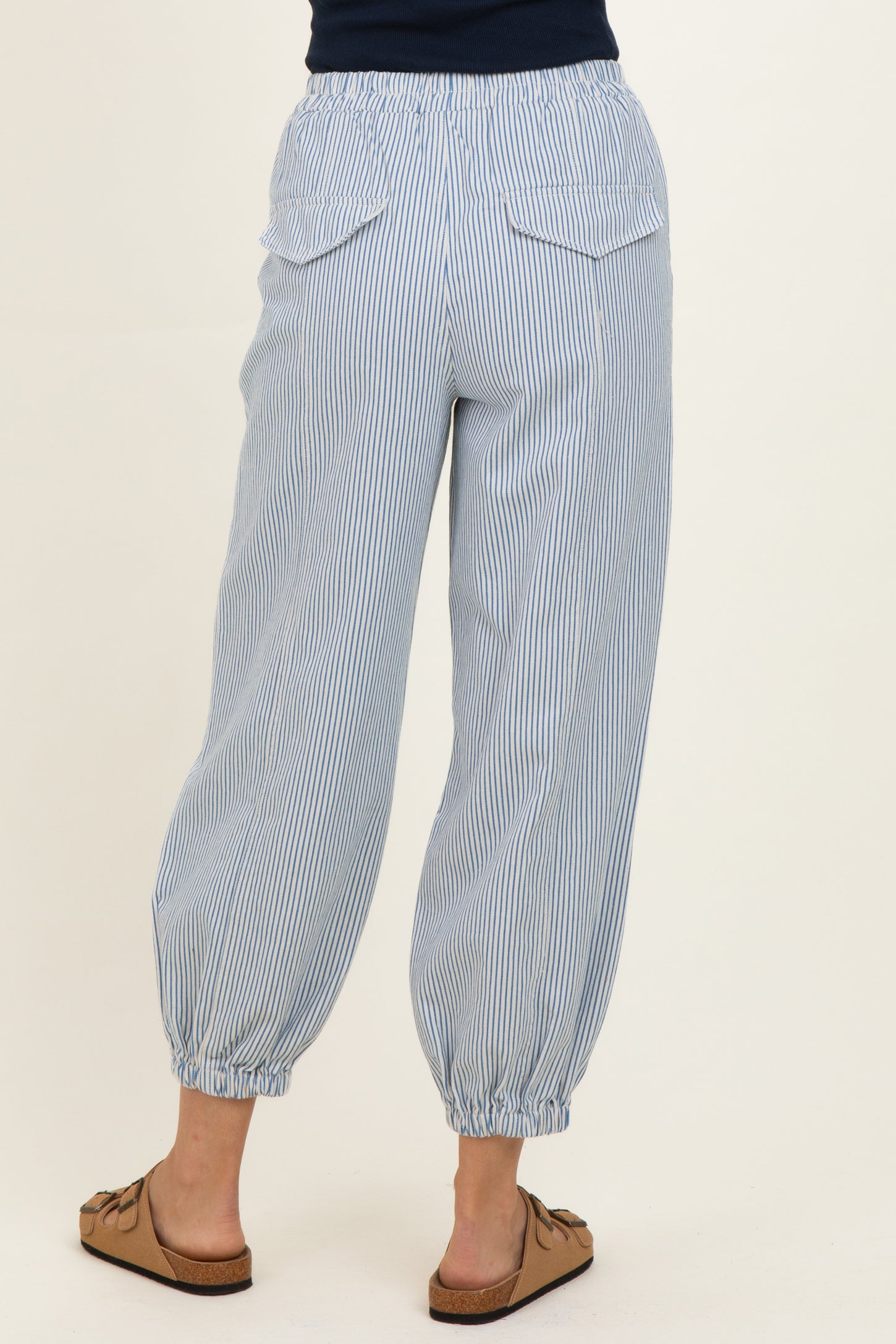 woman wearing light blue striped jogger pants with elastic waistband and cuffed ankles, showing back view