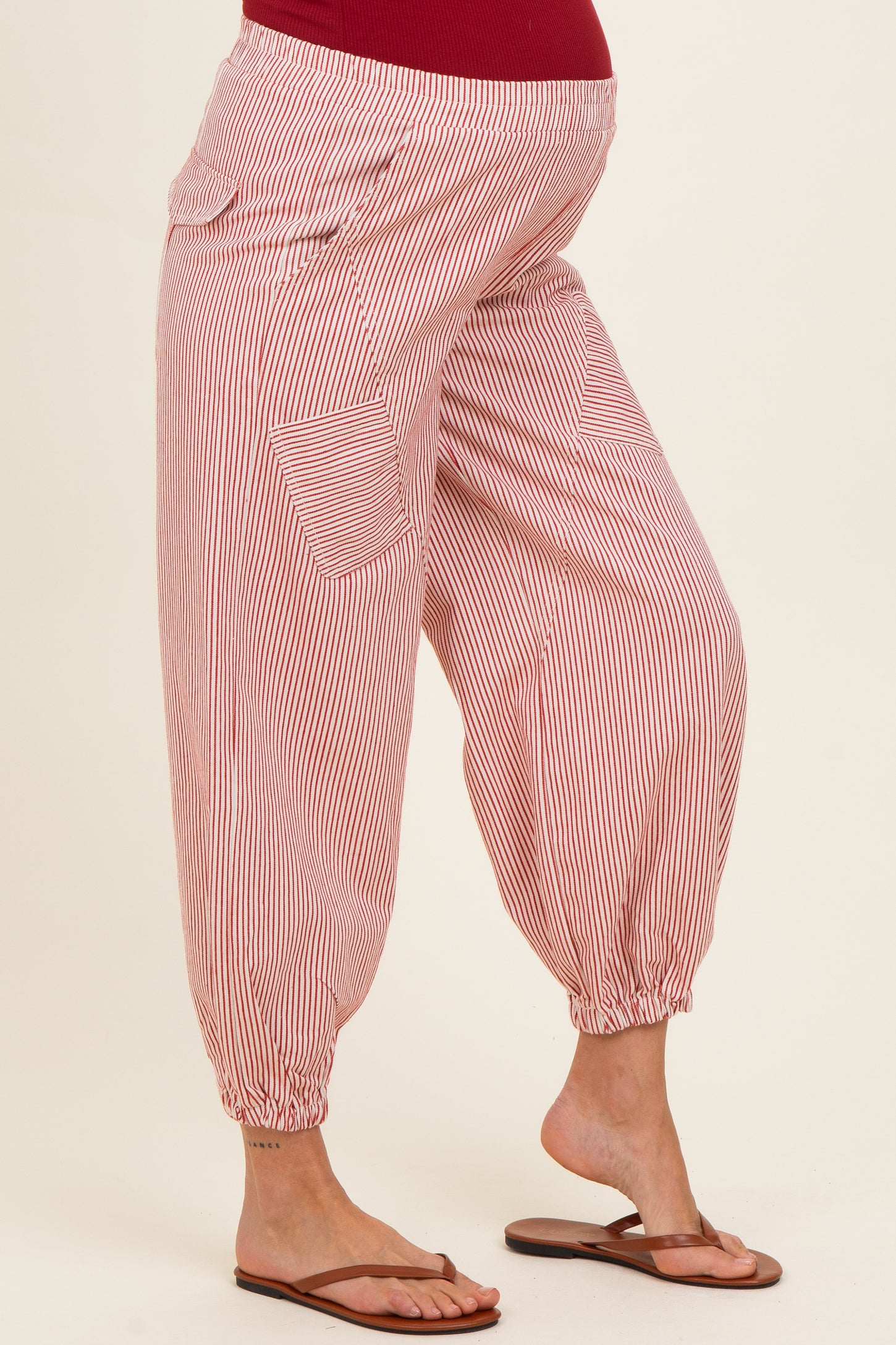 woman wearing red and white striped maternity harem pants with elastic cuffs and side pockets, showing a baby bump
