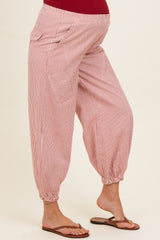 woman wearing red and white striped maternity harem pants with elastic cuffs and side pockets, showing a baby bump
