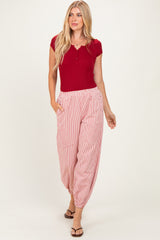 woman wearing a red short sleeve henley top and red and white striped flowy pants