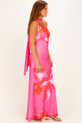 woman wearing a pink floral maxi dress with a halter neck and a matching scarf draped over her shoulder