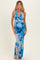 woman wearing a blue floral halter neck maternity dress, showing her baby bump