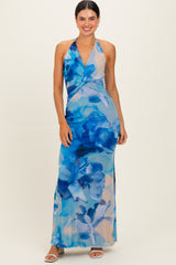 woman wearing a floral maxi dress in blue hues with a halter neckline and twist detail