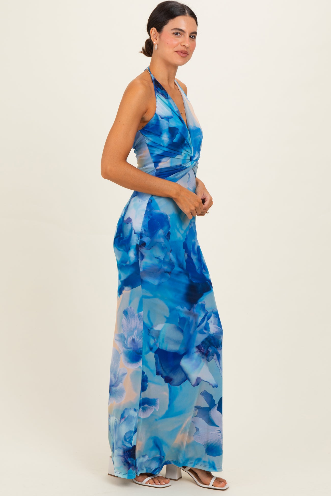 woman wearing a floral blue halter neck maxi dress with a twisted front detail