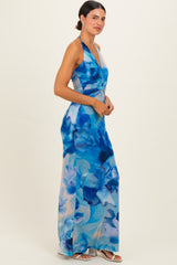 woman wearing a floral blue halter neck maxi dress with a twisted front detail