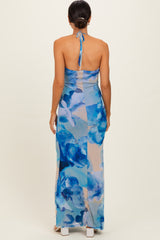 woman wearing a backless blue floral maxi dress with a halter neck and a fitted silhouette