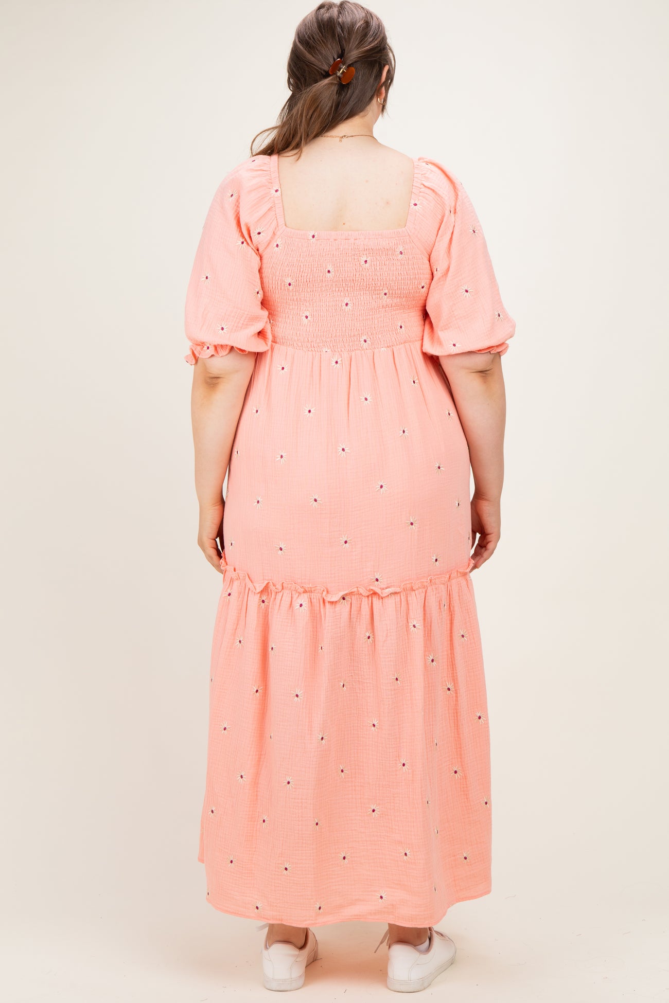woman wearing a pink maternity plus maxi dress with puff sleeves and floral embroidery on the back