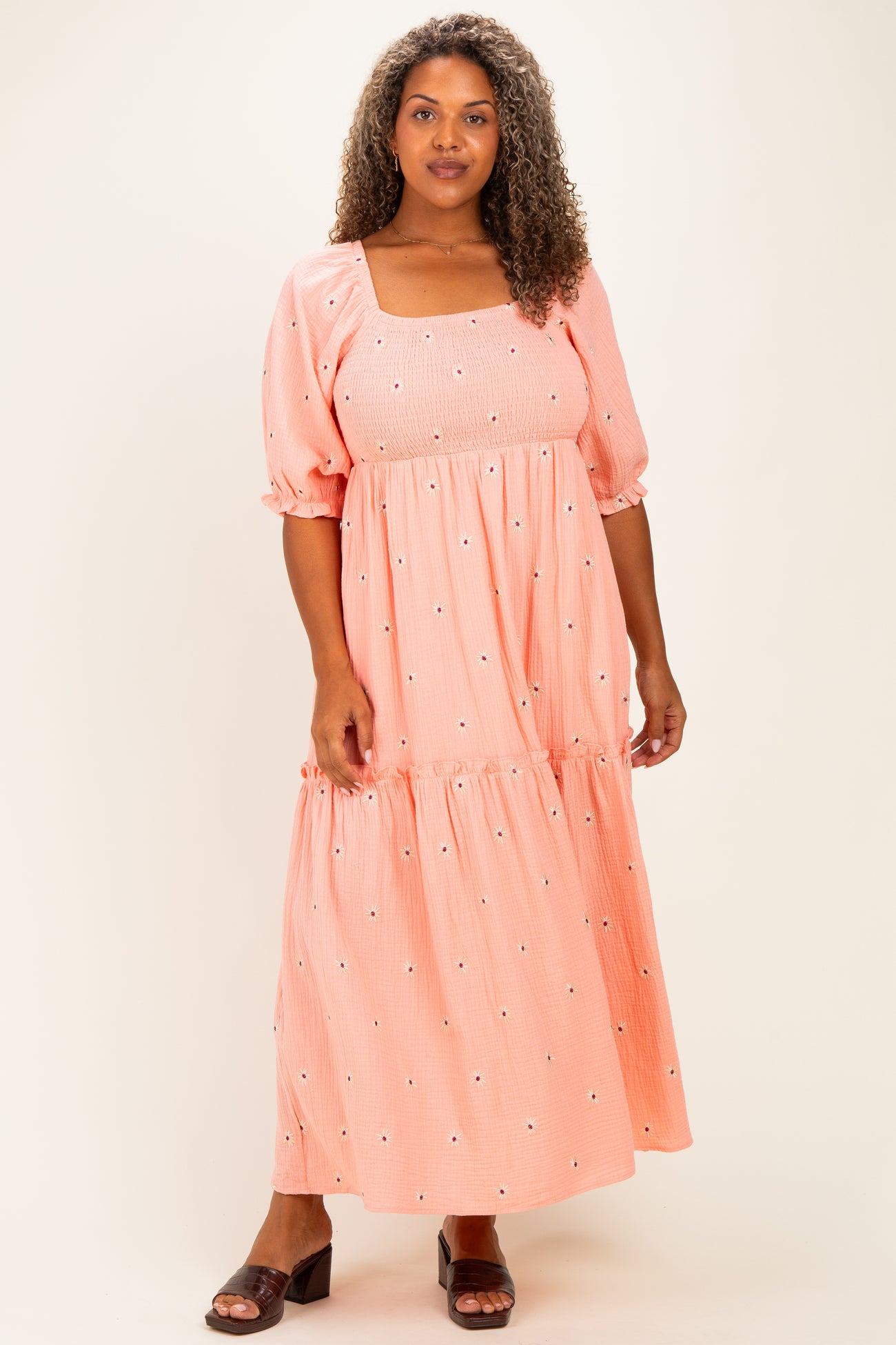 woman wearing a coral maxi dress with puff sleeves and floral embroidery details