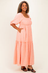 woman wearing a peach puff sleeve maxi dress with a tiered skirt and pockets, featuring floral embroidery