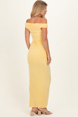 woman wearing a yellow off-shoulder maxi dress, showcasing a fitted style and ruching detail from the back