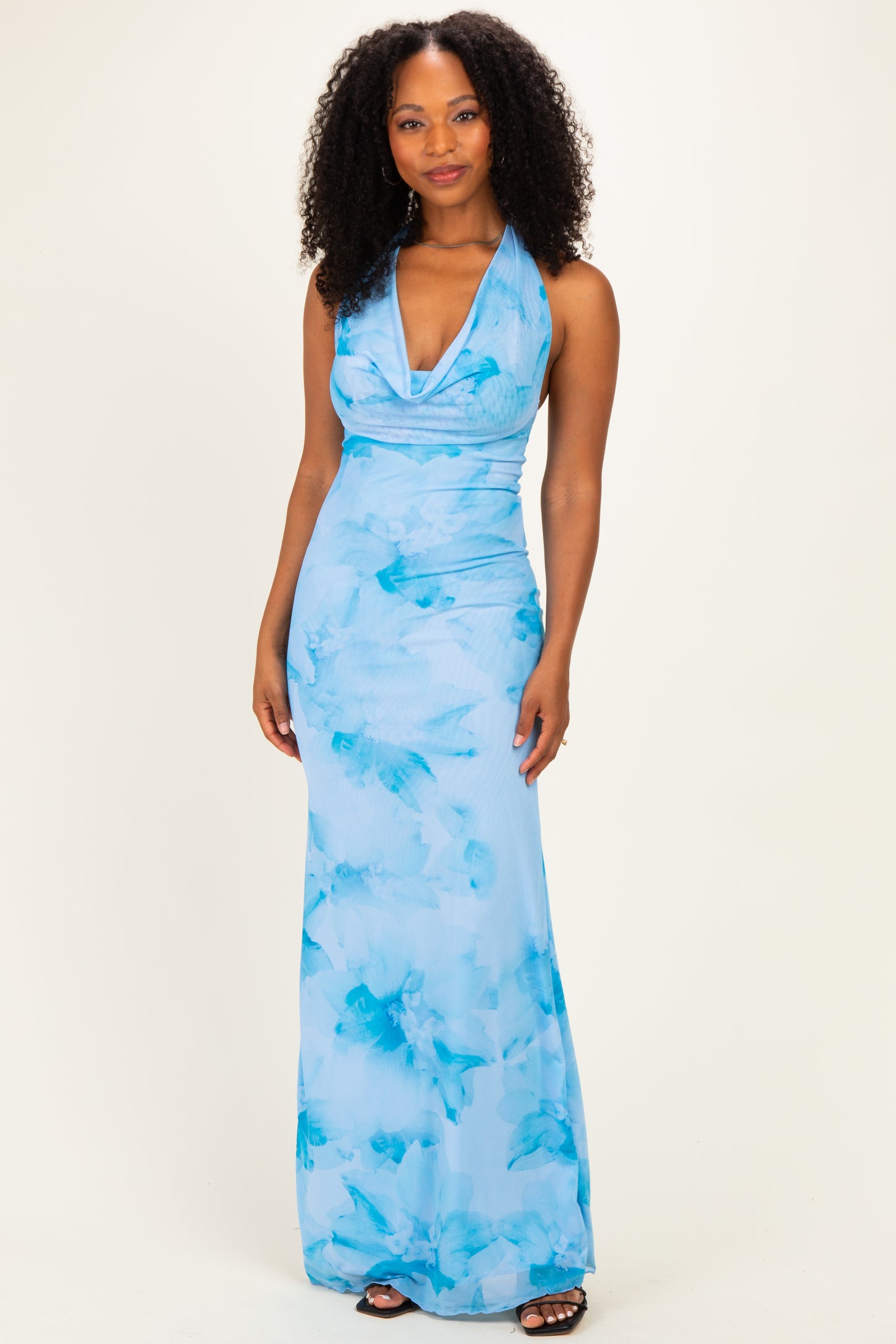 woman wearing a light blue halter neck maxi dress with a floral print and a fitted silhouette