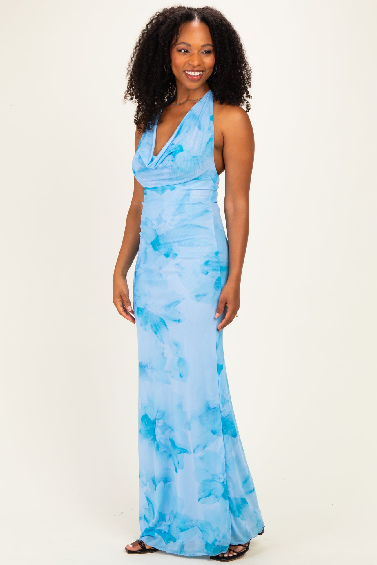woman wearing a flowy light blue halter neck dress with a floral pattern and fitted silhouette