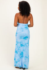woman wearing a backless blue floral maxi dress with a fitted silhouette and flowing skirt