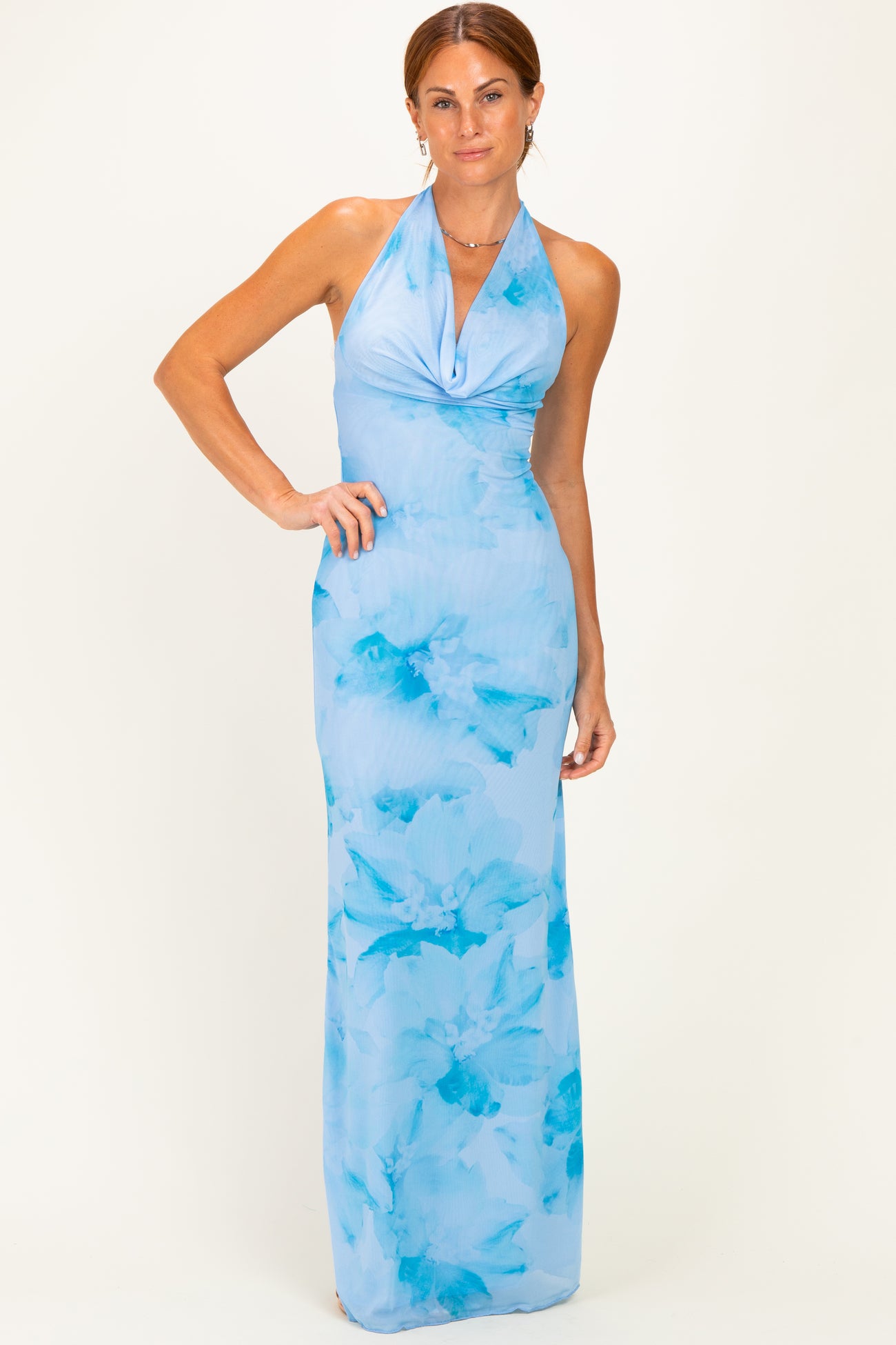 woman wearing a light blue halter neck maxi dress with blue floral prints