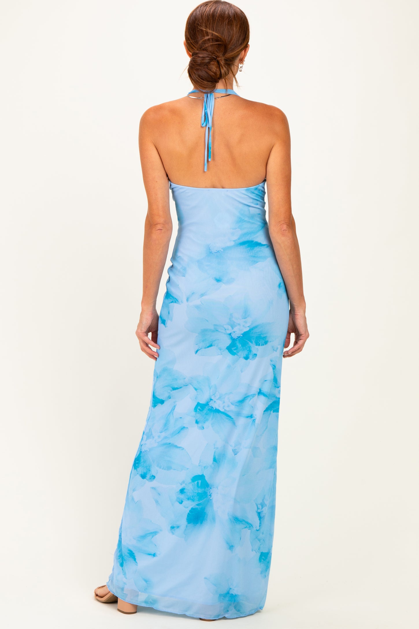 woman wearing a light blue floral maxi dress with a halter neck and open back, showing a smooth fit and flowy silhouette