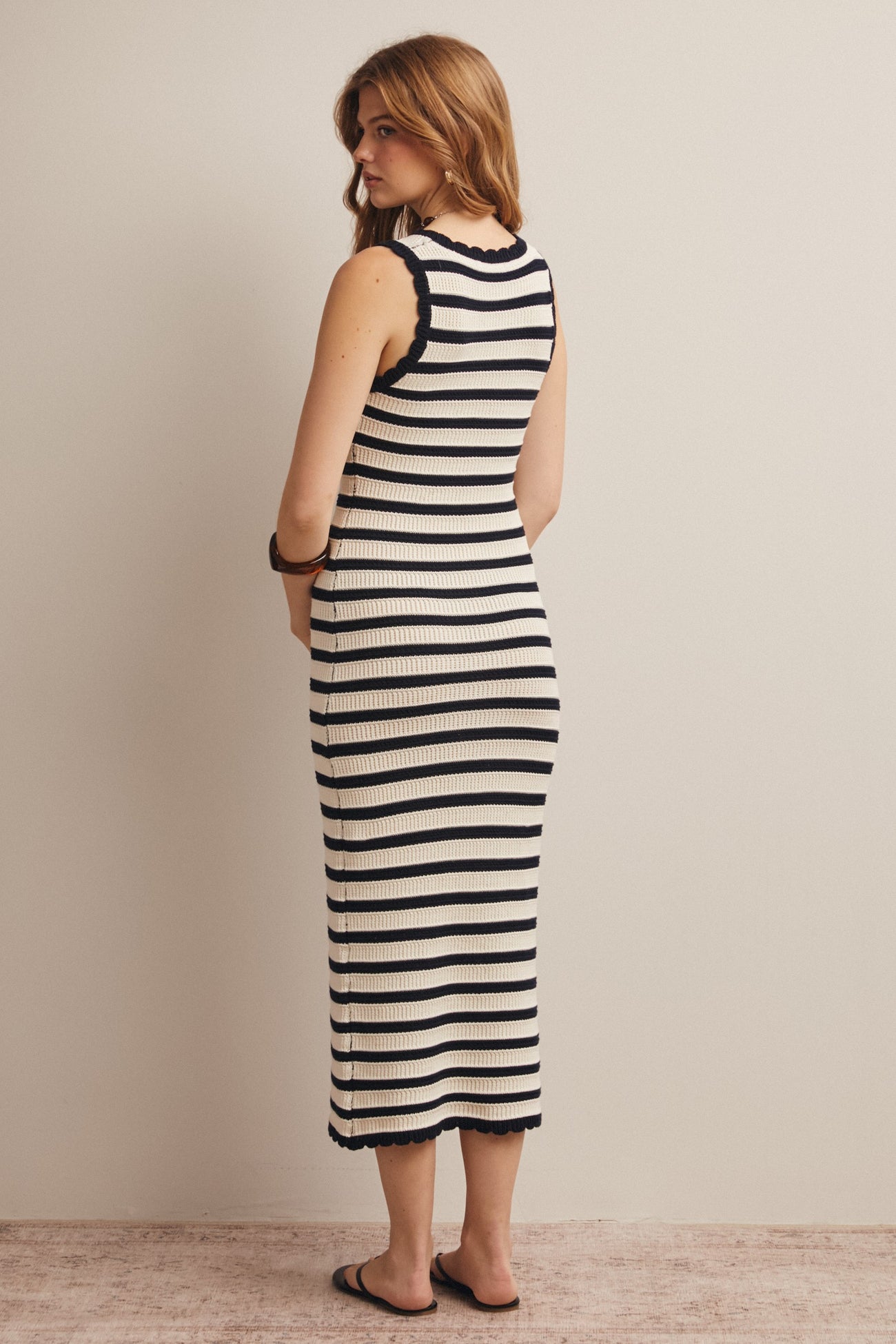 woman wearing a fitted black and white striped midi dress with a scalloped hem and back view showing the dress length