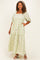 woman wearing a light green plus size maxi dress with floral embroidery and puff sleeves, standing with hands in pockets